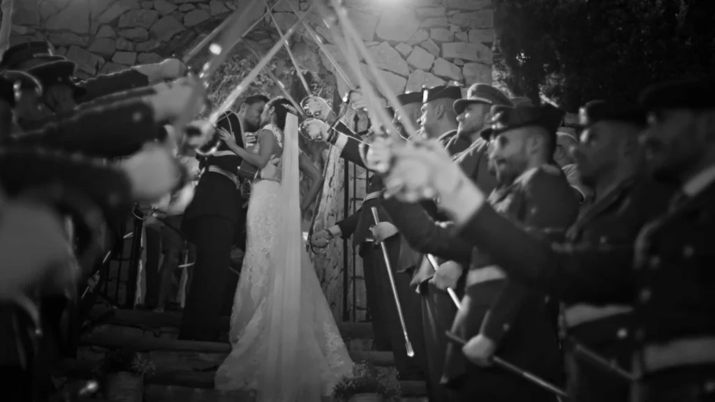 Saber arch kiss in black and white — dramatic, timeless style.