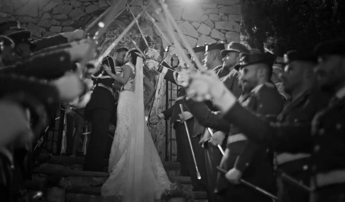 Saber arch kiss in black and white — dramatic, timeless style.